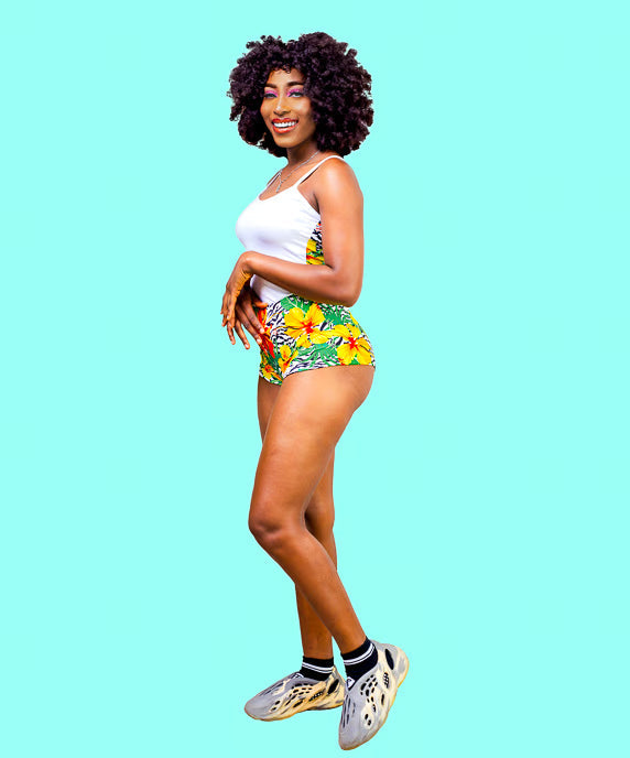 Woman with a white Cami top and tropical print shorts caribbean sleepwear set on turquiose background