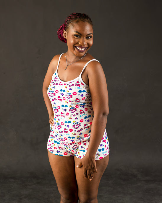 Woman with white cami top and tropical caribbean shorts pajama set on a turquiose background