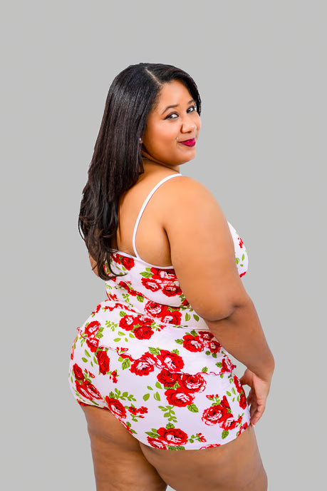 Plus size woman wearing a white 2-piece sleepwear set with red roses print on a gray background