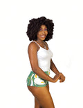 Woman wearing a white tank top and green leaf shorts sleepwear set on a white background