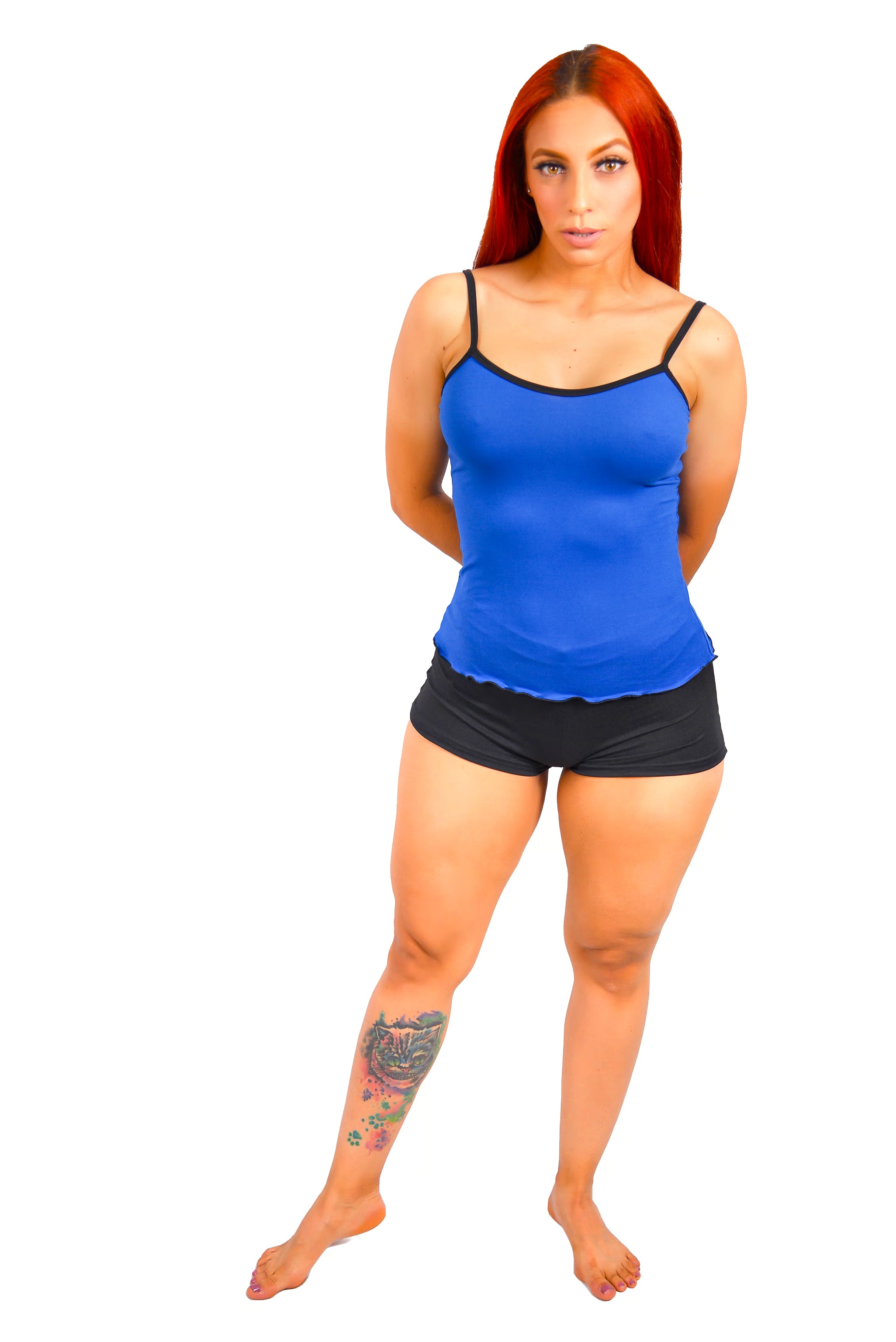 Beautiful Woman wearing a blue tank top and black shorts with tattoo on lower leg on a white background