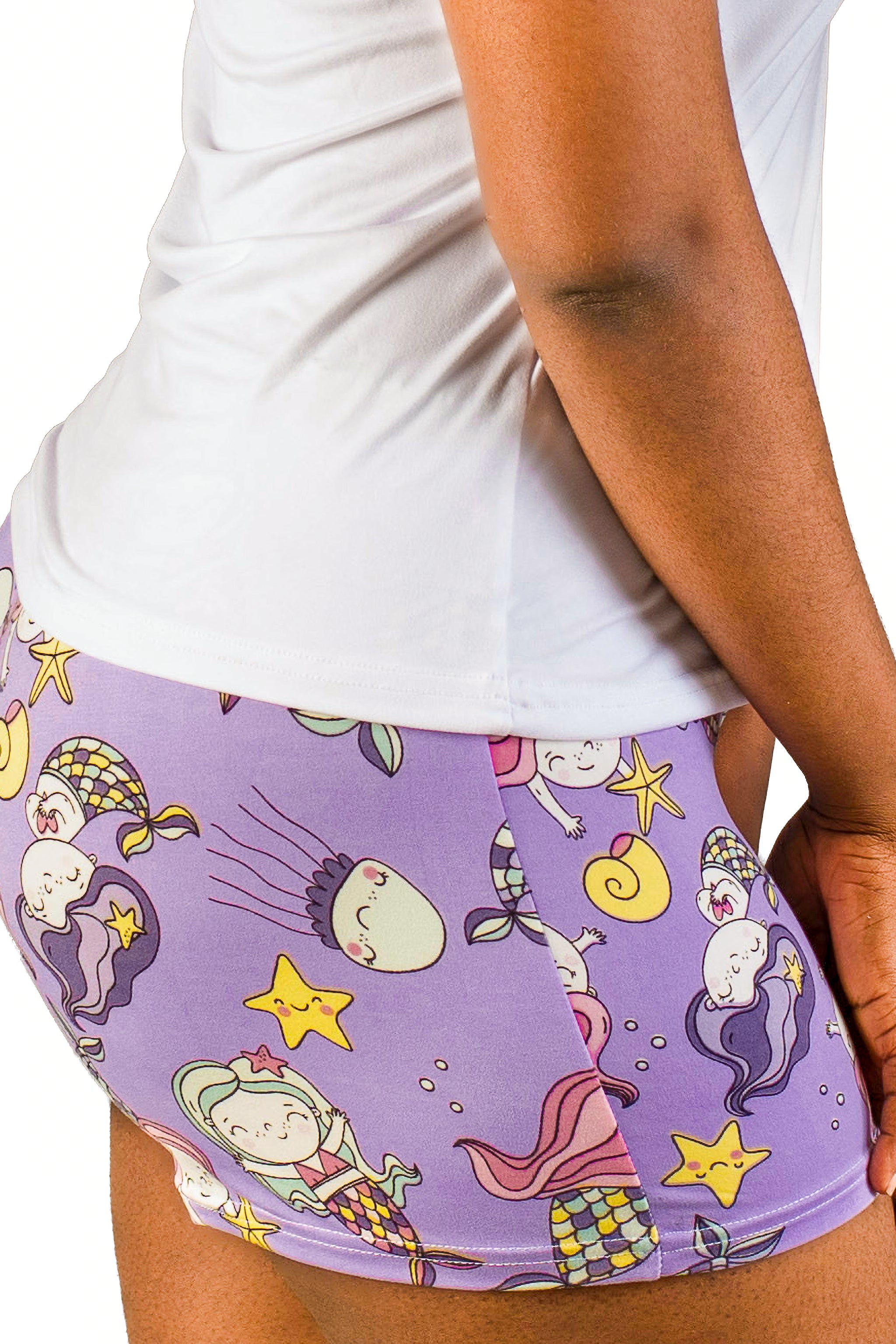 Purple shorts with mermaid pattern worn by a person on a white background