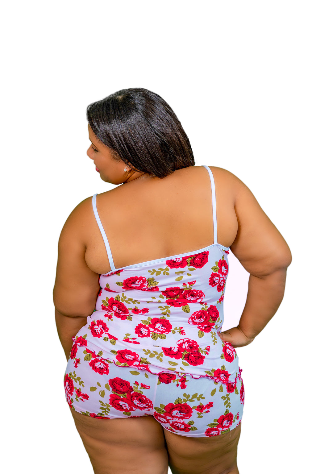 Woman with back turned  wearing a rose pajama short set with red flowers on a white background