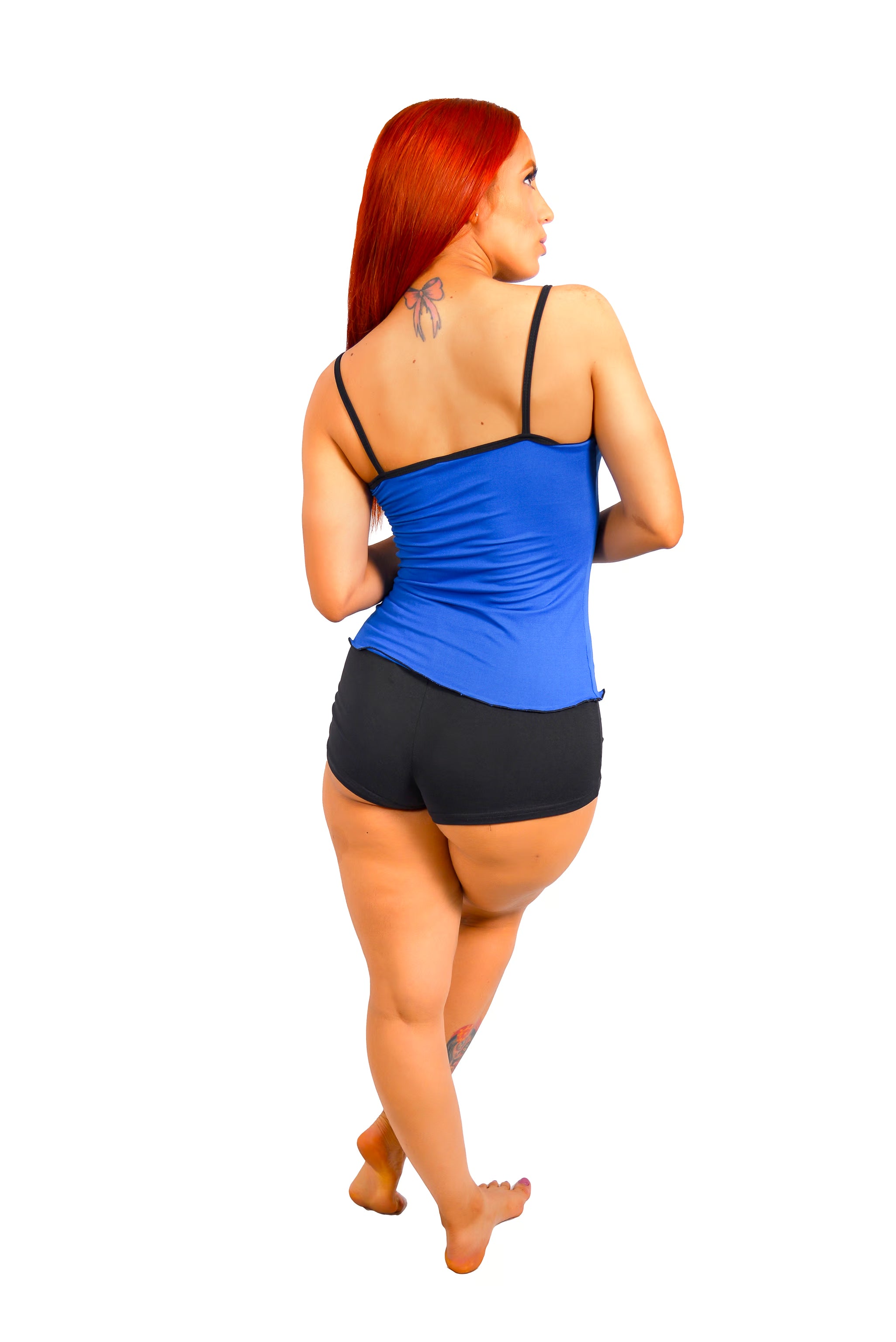 Woman posing in a blue tank top and black shorts on a white background