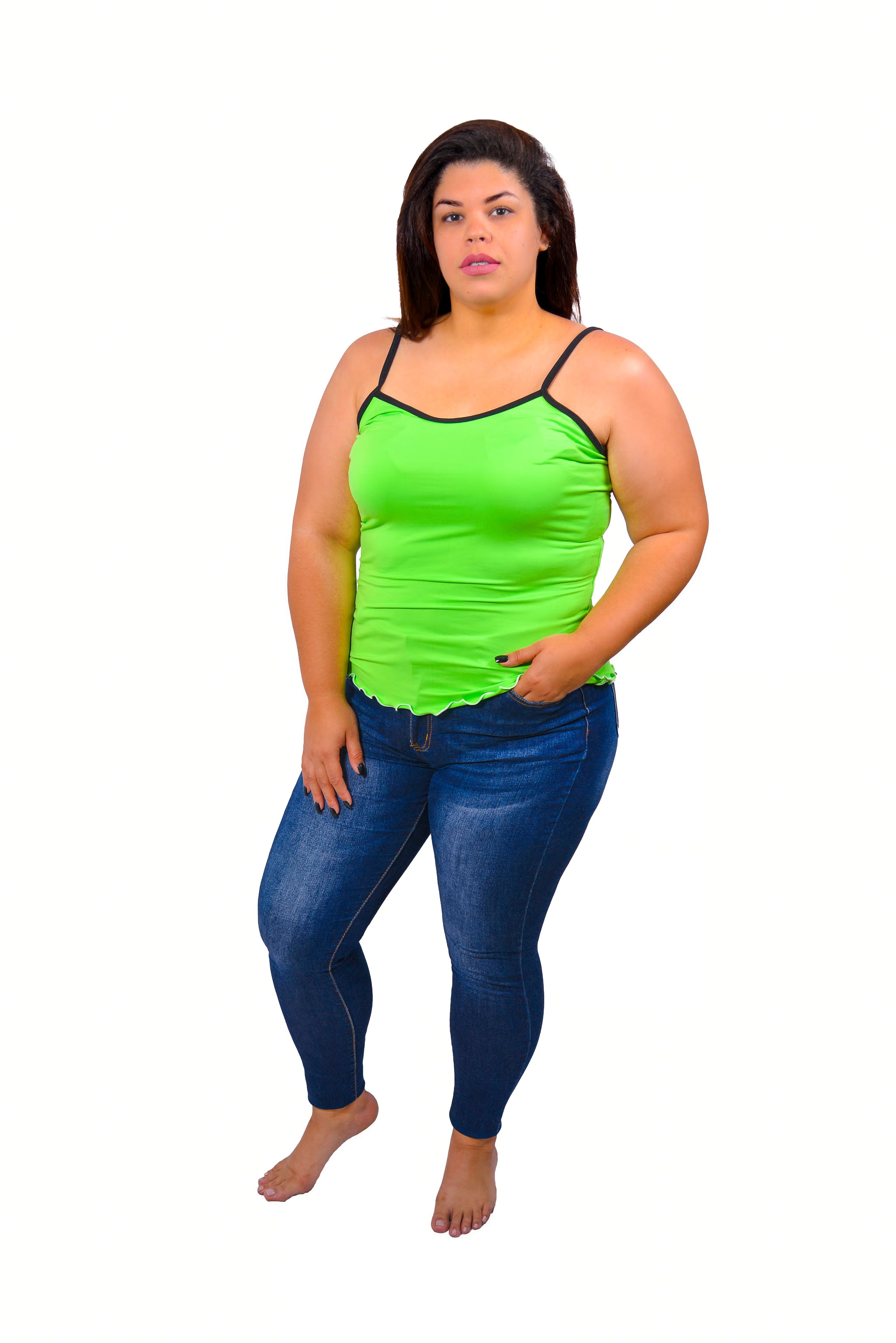 Woman wearing a bright green Cami pajama top and blue jeans on a white background