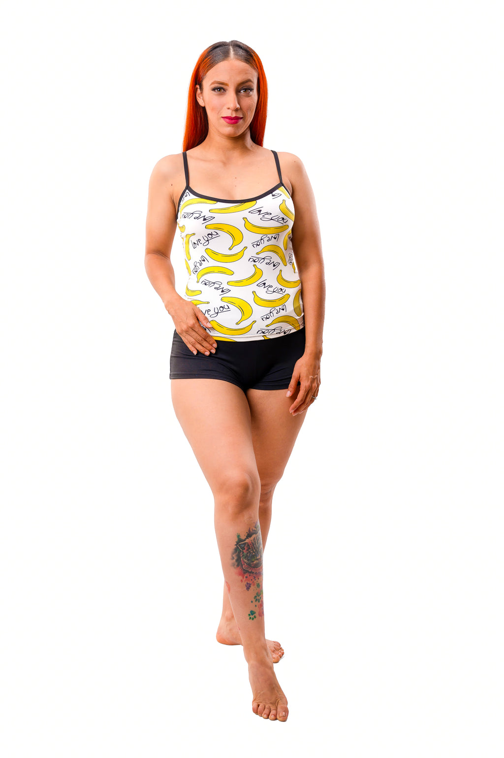 Woman wearing playful banana print pajama set on white cami and black shorts set on white background