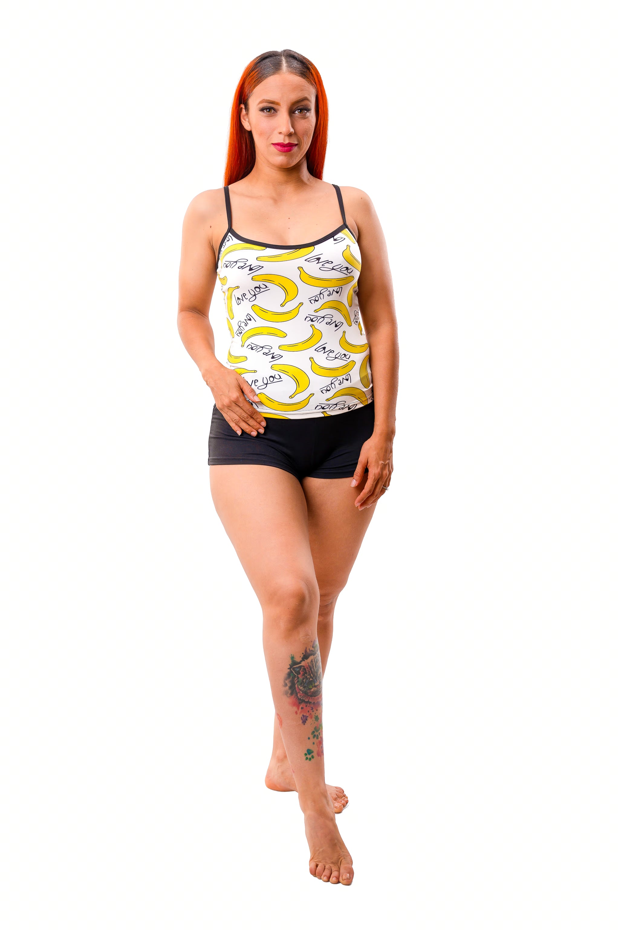 Woman wearing playful banana print pajama set on white cami and black shorts set on white background