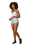 Woman wearing a white Cami top, multi-floral print shorts, and black socks on a white background