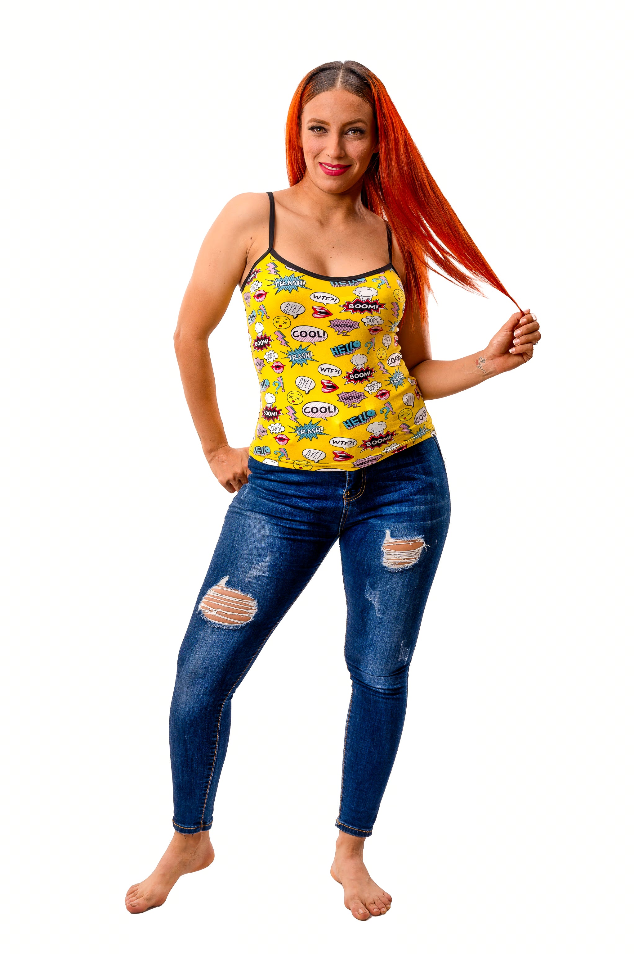 Woman wearing yellow pop art camisole with comic-style captions styled with jeans on white background