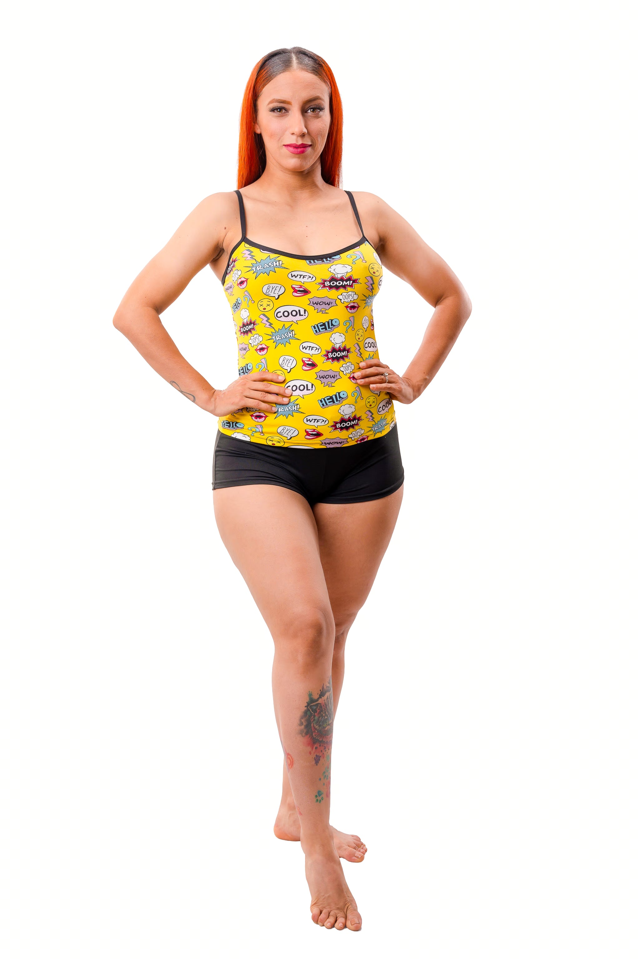 Woman wearing a yellow cami top with graphic design and black shorts on a white background
