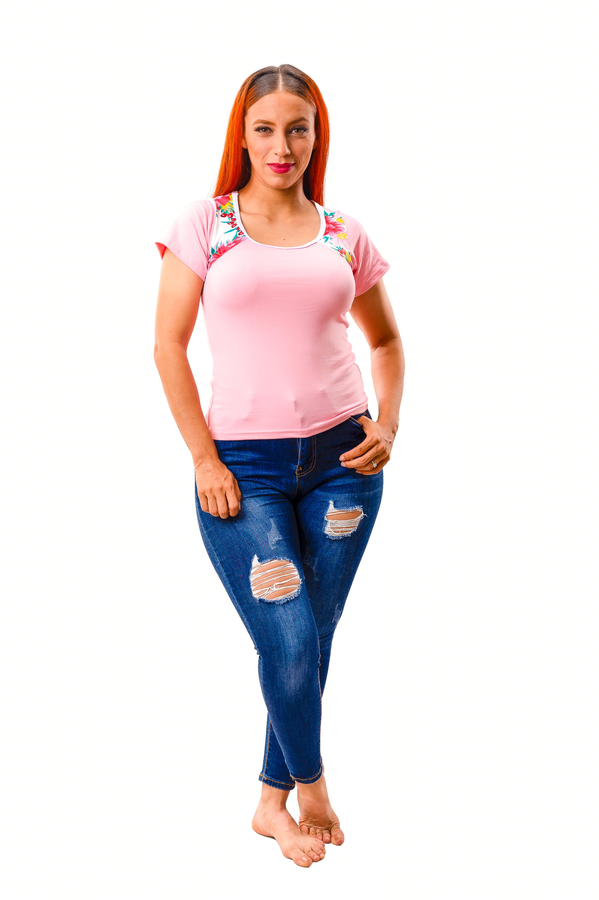 Woman wearing a pink pajama top with colorful accents and blue jeans on a white background