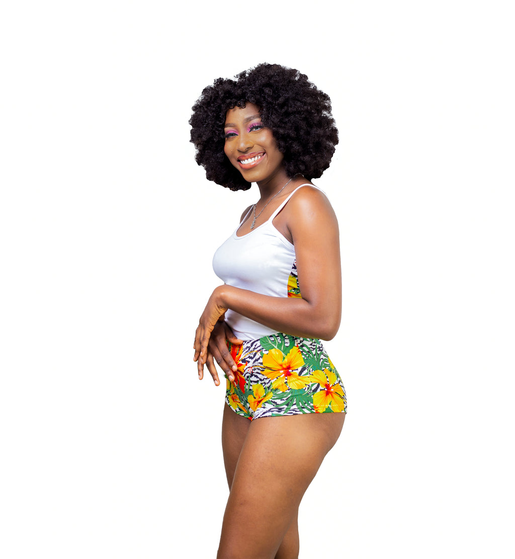 Carribean Woman wearing a white Cami top and tropical print shorts on a white background