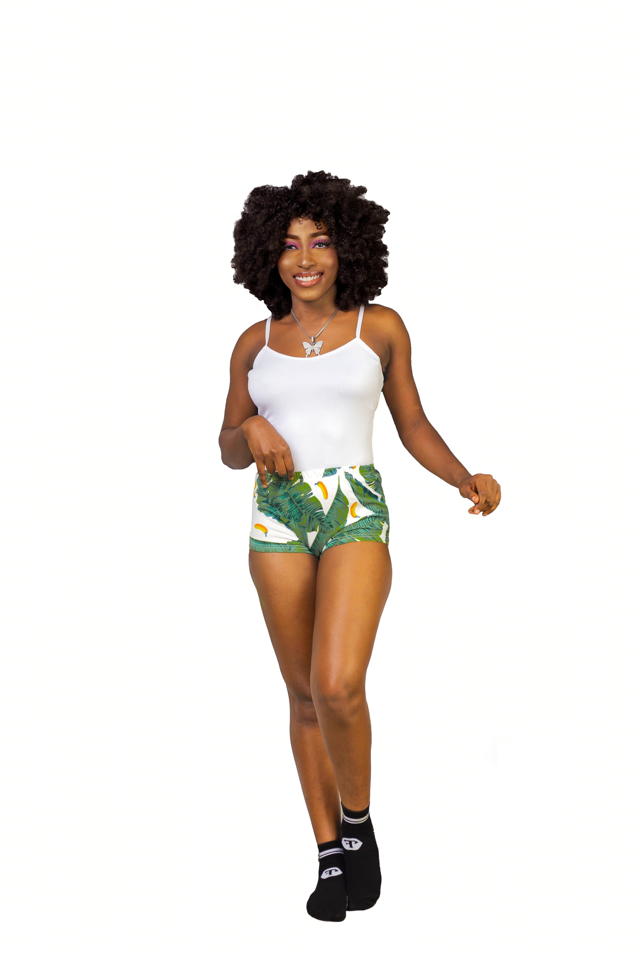Woman wearing a white tank top and green leaf-patterned shorts on a white background